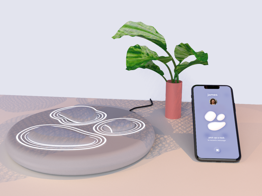 WeToca Rocks and Base are positioned on a table next to a plant and a phone with the WeToca App installed. The Rocks are very similar to natural pebbles.